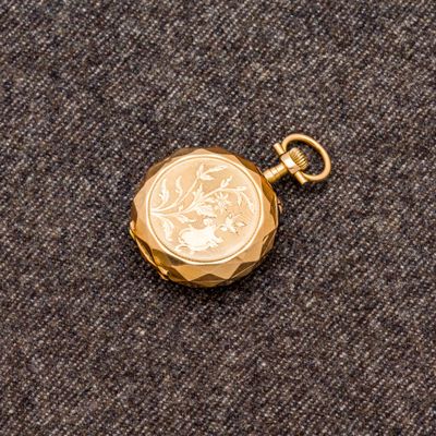 un gros plan d'une montre de poche en or sur laquelle repose une pièce de monnaie