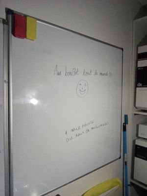 un tableau blanc sur lequel sont écrites des notes, dans un coin de la pièce