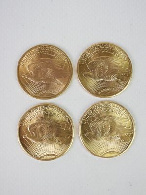 quatre pièces d'or superposées sur une surface blanche