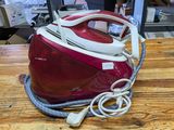 a red and white steam iron sitting on a wooden table
