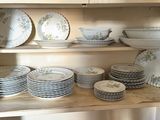 many plates and bowls on a shelf in the kitchen