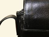 a black leather purse with a metal handle on a table