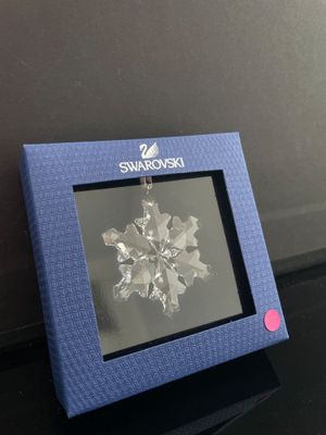 une décoration en forme de flocon de neige dans un cadre bleu, posée sur une table noire