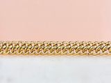 a close up of a gold chain bracelet on a pink background