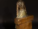 a bronze statue of a woman sitting on top of a wooden box