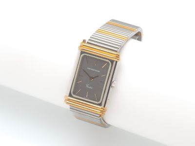 une montre-bracelet argentée et dorée posée sur une surface blanche