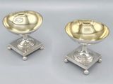 paire de bougeoirs plaqués argent sur des socles, sur fond gris