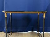 a black and gold console table on a wooden floor