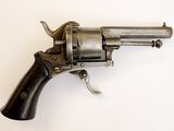 un vieux revolver avec une poignée en bois sur une surface blanche