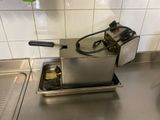 plan de travail en acier inoxydable équipé d'une friteuse et d'un évier dans une cuisine professionnelle