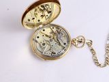 a gold pocket watch with a chain on a white surface