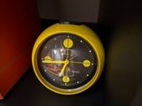 a yellow clock sitting on a black shelf next to a red box