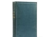 an old book with a green cover sitting on a white surface