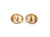 two pairs of earrings with a painting on them sitting on a white surface