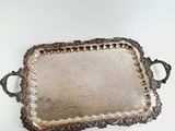 an ornate silver tray with handles and handles on a white surface
