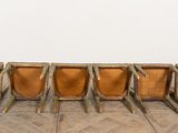 six chairs in a row on a wooden floor in front of a white wall
