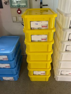 des récipients en plastique jaunes et bleus empilés les uns sur les autres dans une pièce