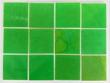 a close up of a green tile on a white surface
