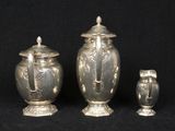 three silver vases and an owl on a black background
