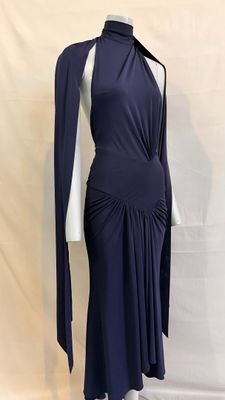 une femme vêtue d'une robe bleue et d'une cape est debout sur un mannequin