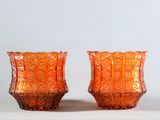 deux vases en verre orange posés sur une surface blanche