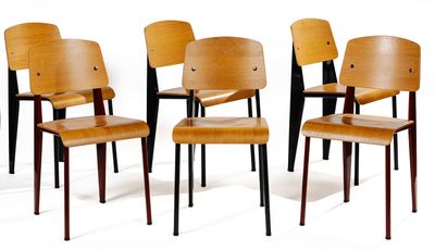 four wooden chairs are lined up against a white wall
