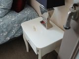 un lit recouvert d'une couette bleue et blanche, à côté d'une petite table blanche sur laquelle est posée une lampe