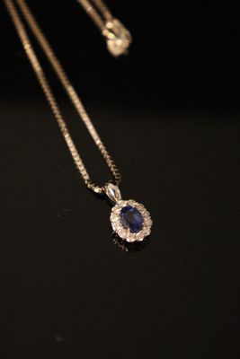 a close up of a blue sapphire and diamond pendant on a chain