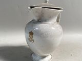 un petit vase blanc muni d'un couvercle, posé sur une table