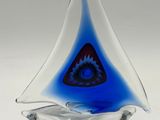 a blue and white glass sailboat on a white surface