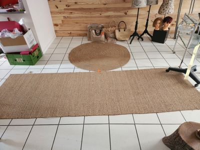 un tapis posé à même le sol dans une pièce, avec un mur en bois en arrière-plan