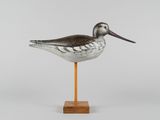 un oiseau au long bec posé sur un socle en bois