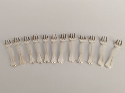 six fourchettes sont disposées en rangée sur une surface blanche