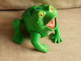a green frog that is sitting on a couch