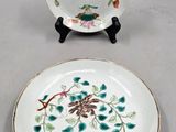 two plates with floral designs on them sitting on a white surface