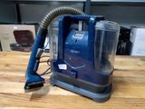 un aspirateur bleu posé sur une table en bois