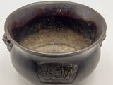 a black bowl with a handle on a white surface