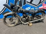 une vieille moto garée devant un mur recouvert de graffitis