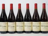 six bottles of wine are lined up on a white surface