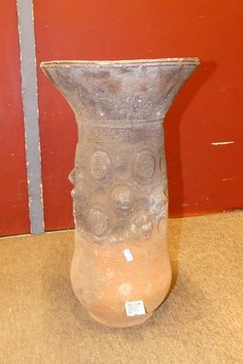 un vase posé par terre devant un mur rouge