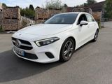 the mercedes cla is parked in a parking lot near a stone wall