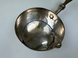 a metal bowl with a wooden handle on a table