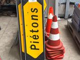 a yellow and black stop sign next to a red and white traffic cone