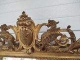 a mirror that has a gold frame with a picture on it
