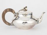 une théière ancienne en argent avec une anse en bois, sur fond blanc