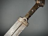 a close up of a knife on a table with a gray background