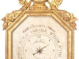 a gold clock with a clock face and a wreath around it