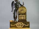 une statue représentant un ange tenant une horloge posée sur un socle