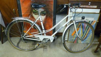 un vélo blanc garé à côté d'un tableau accroché au mur