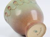 a brown and green vase with a lid on a white surface
